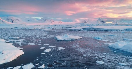 Wall Mural - Incredible bright sunset over Antarctica landscape. Ice, cold ocean, glaciers, snow-capped mountains, colorful cloudy sky. Breathtaking journey over frozen untouched nature. Aerial drone flight
