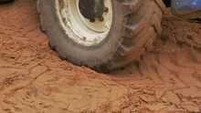 Close Up Of Big Tractor Wheel Driving On Soft Sand Ground