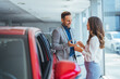 © Dragana Gordic - Portrait of a beautiful young couple choosing a new car at a car dealership. Buying a long-awaited car. Couple buying the car. Pair in a car salon. Husband with vife choose the automobile