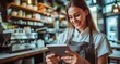 © Radomir Jovanovic - A cheerful woman expertly multitasks, effortlessly balancing her tablet and a bottle on a shelf, as she smiles warmly at the camera in her quaint indoor kitchen