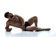 Full length portrait of young naked athlete man lying on floor against white background. Male model posing in underwear in studio. Concept of beauty care, male health, masculinity. Ad