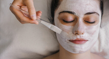 Wall Mural - Close-up shot of a woman getting facial treatment with clay mask. Cosmetology and spa