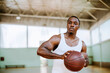 © Marko Geber - Portrait of a young fit man holding basketball at indoor court