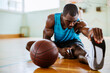 © Marko Geber - Young man stretching before playing basketball in an indoor basketball gym