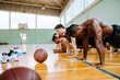 © Marko Geber - Diverse young men doing push ups in basketball gym