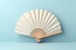 © Vovmar - Wooden white open fan on a blue background. Generated by artificial intelligence