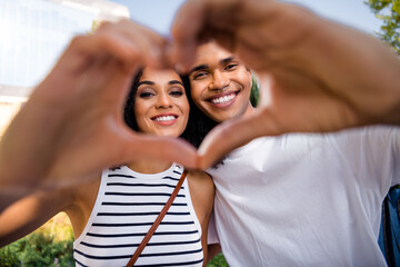 Sticker - Photo of attractive lovely cheerful couple wife and husband showing in camera heart shape romantic date outside