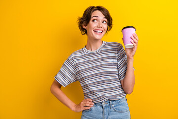 Sticker - Photo of cheerful glad girl dressed trendy clothes hold mug caffeine drink look empty space offer isolated on yellow color background