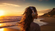 Jeune femme aux cheveux longs écoutant de la musique avec un casque sur les oreilles. Devant un coucher de soleil sur une plage. Paysage, musique, détente, calme. Pour conception et création graphique