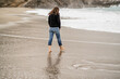Full-length rear view of woman walking barefoot on the foreshore.