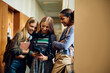 © Drazen - Happy teenage girls using smart phone in hallway at high school.