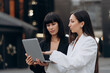 © MZaitsev - Meeting of two business women. Two young women dressed in business suits are discussing a project on a city street.