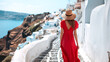 © Cla78 - A woman with a straw hat and a red dress in Santorini