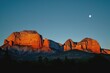 the mountains and bluffs near sedona at sunset with the moon above