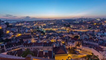 Wall Mural - Lisbon after sunset aerial panoramic view of city centre with roofs at autumn day to night transition timelapse, Portugal. Top view from Sophia de Mello Breyner Andresen viewpoint. Lights turning on