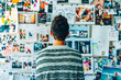 © mila103 - person standing in front of a wall covered in pictures and magazine clippings, creating a vision board