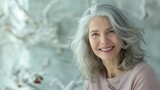Fototapeta Do akwarium - Portrait of a cheerful elderly woman with stylish gray hair, laughing softly, light and airy background. Natural beauty, lively and content expression