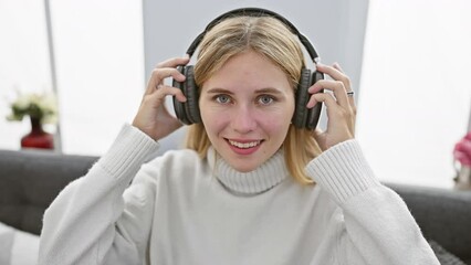 Poster - Blonde woman enjoying music with headphones, smiling indoors at home.