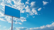 Blank Blue Traffic Sign Against Blue Sky Background With White Clouds. Mockup Traffic Sign With Copy Space.