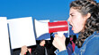 Mocap. A woman shouts into a megaphone in front of people holding signs with no lettering.