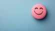 A pink smiling ball with a drawn face on a blue background