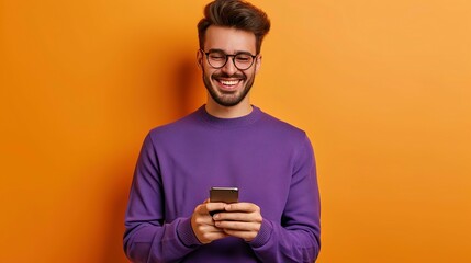 cheerful man in eyeglasses and purple sweater using smartphone on orange background, texting