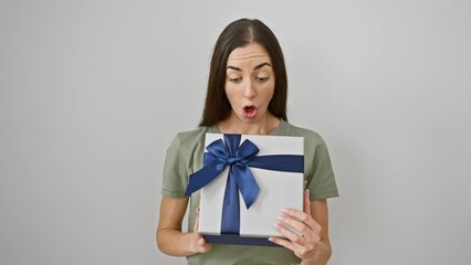 Poster - Beautiful young hispanic woman in disbelief, amazed and scared, mouth open holding birthday gift in shock. surprised female portrait isolated on white. astonishing expression of surprise, fear and wow