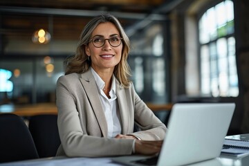 Wall Mural - Happy mid aged professional business woman working in office with laptop looking away at copy space. Smiling mature businesswoman executive or lawyer at workplace thinking of new ideas, Generative AI