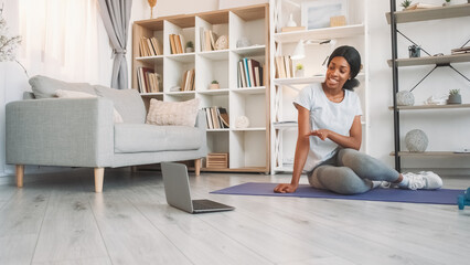 Wall Mural - Fitness vlog. Pilates course. Fit professional yoga instructor woman teaching training at laptop video class on sports mat on floor in home living room.