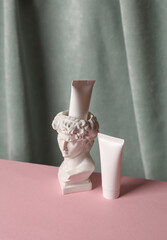 Wall Mural - David bust vase with cream tubes against the background of curtain. Aesthetic beauty still life. Minimalism.