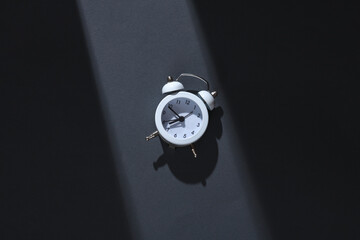 Wall Mural - Alarm clock on gray background with stripe of light and shadow. Minimalism. Concept photo