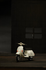 Photo of an old miniature Vespa which is also called a scooter. Photographed with a not so bright background to isolate the white Vespa object