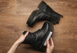 Hands applying shoe polish to black leather boots