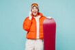 © ViDi Studio - Young woman wears warm padded windbreaker jacket hat ski goggles mask hold snowboard talk on mobile cell phone travel rest spend weekend winter season in mountains isolated on plain blue background.