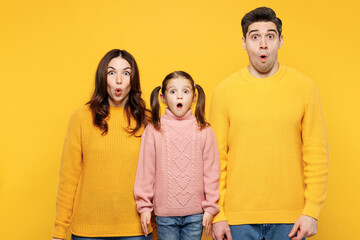 Poster - Young sad surprised astonished startled scared shocked parent mom dad with child kid girl 7-8 years old wear pink knitted sweater casual clothes isolated on plain yellow background Family day concept