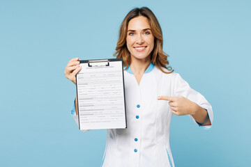 Wall Mural - Female doctor woman wears white gown suit work in hospital clinic office hold point finger on clipboard with registration form document isolated on plain blue background. Health care medicine concept.