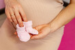 © elenbessonova - Anticipation of joy. Pregnant woman holding pink baby socks. A future mothers hands tenderly cradle soft pink baby socks, a symbol of the awaited joy and a lifes new chapter.