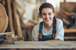 © PixelGallery - Portrait of young female carpenter sitting at table in her workshop