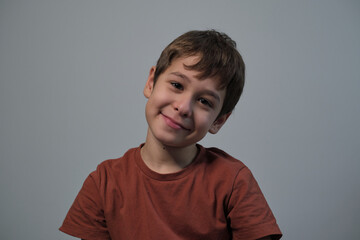 Smiling boy with a joyful expression, posing against a grey backdrop. His smile reflects the carefree and happy nature of childhood.