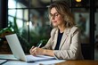 © Imagery Innovators - Busy mature mid aged business woman professional in her 40s writing notes finance report overview, lawyer checking document, working on laptop computer device sitting at desk in office. Generative AI
