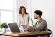 © F8  \ Suport Ukraine - Professionals standing in an office and using a laptop together. Two young business people discussing a project.