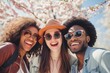 a group of young diverse cheerful and happy people students taking a selfie on a wide angle on a stroll through nature during spring break vacation holiday, blossom and tree bloom in the background