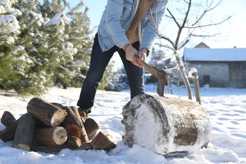 Man chopping wood with axe outdoors on winter day, closeup