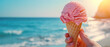 Close-up of a hand holding ice cream in a waffle cone on a sunny summer day at sea, copy space banner