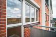 A Modern kitchen viewed through windows from an exterior balcony, revealing a scenic view of rolling hills and sky.