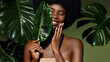 Organic cosmetic concept. Green beauty portrait. Young African American woman smiling and holding banana leaf against tropical green leaf. Natural cosmetics concept.
