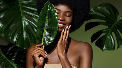 Wall Mural - organic cosmetic concept. green beauty portrait. young african american woman smiling and holding ba