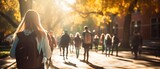 Fototapeta Londyn - Crowd of students walking through a college campus on a sunny day