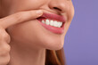 © New Africa - Woman showing her clean teeth on violet background, closeup. Space for text