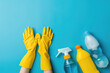 Cleaning essentials including yellow gloves, a sponge, and spray bottles are neatly arranged on a bright blue background.	
